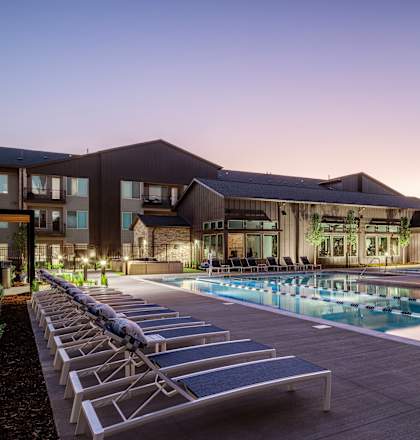 a swimming pool with lounge chairs in front of a building