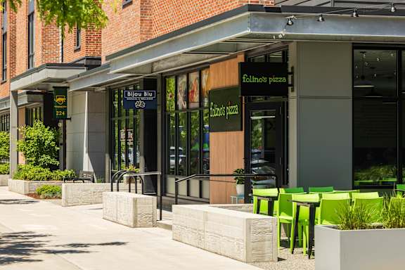 A restaurant with green chairs outside.
