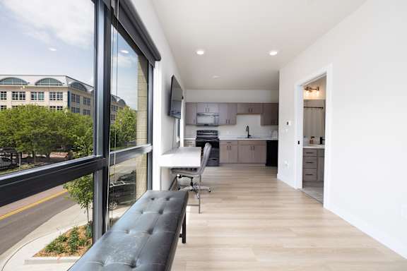 A modern kitchen with a black bench and wooden floors.