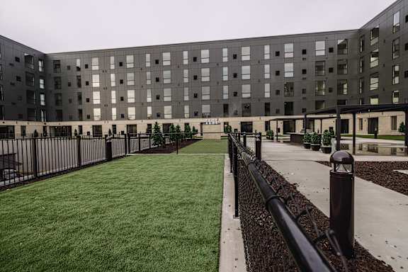 A large building with a black fence and a green lawn in front.