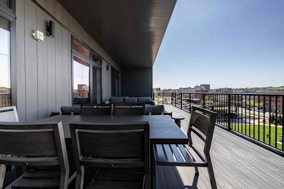 A balcony with a table and chairs overlooking a cityscape.