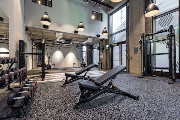 A gym with a variety of equipment including weights and a bench press at Beton Apartments, Wembley, HA9 0SL