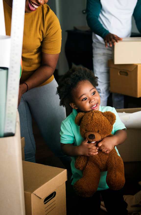 a little girl holding a teddy bear in a living room at Sonder House Apartments, Apartments, Brooklyn Center, MN