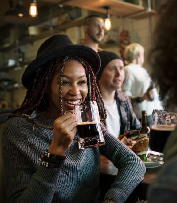 three women sitting at a bar with a glass of beer