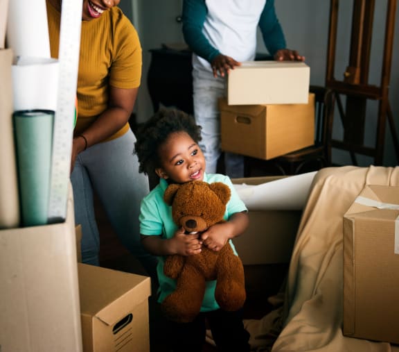 a little girl holding a teddy bear in a living room