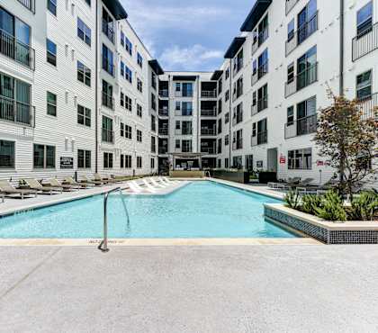 A swimming pool in front of a white building.