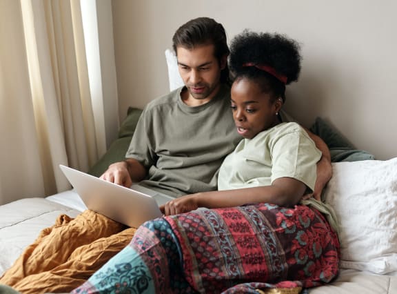 Couple laying on the bed looking at laptop