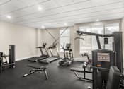 Thumbnail 3 of 8 - A gym with a variety of equipment including treadmills, stationary bikes, and weight machines.