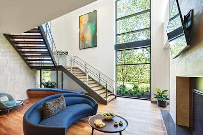 A modern living room with a blue couch and a painting on the wall.