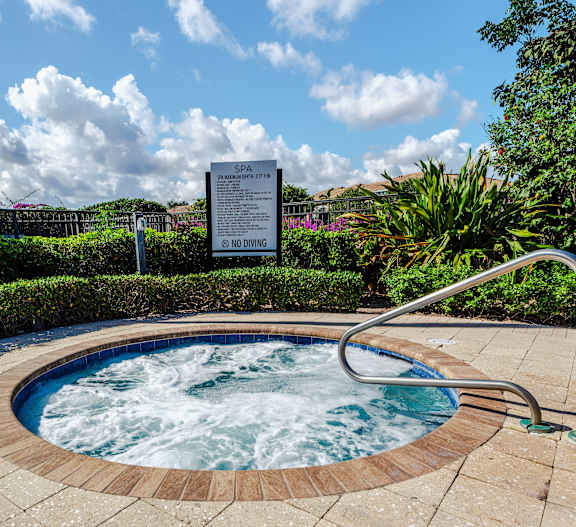 A hot tub in a garden with a sign in the background.