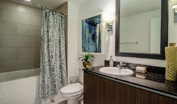 A bathroom with a toilet, sink, and mirror.