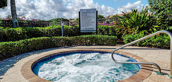 A hot tub in a garden with a sign in the background.