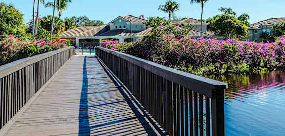 A wooden walkway leads to a building with a white roof and a blue door.