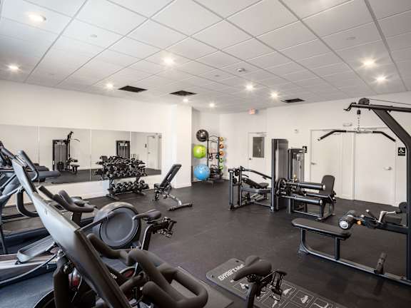 a gym with treadmills and other exercise equipment in a building with white walls