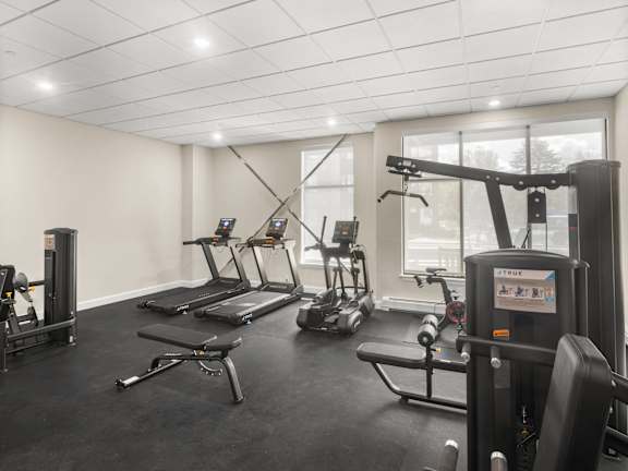 A gym with a variety of equipment including treadmills, stationary bikes, and weight machines.