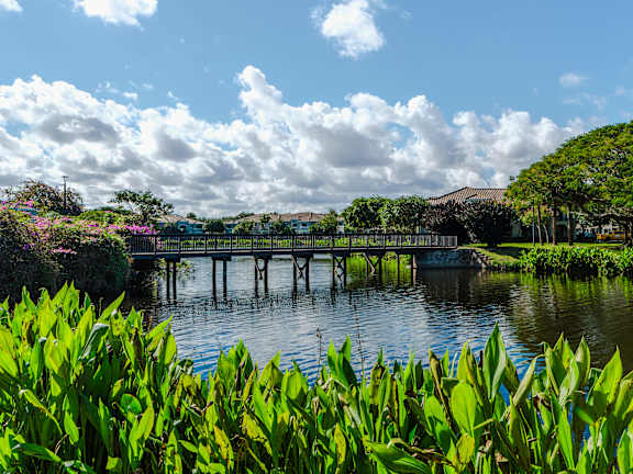 A bridge over a blue lake with a fountain in the middle.