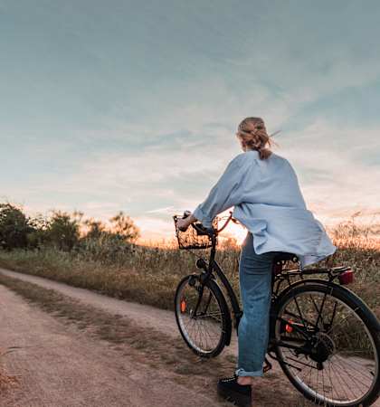 a woman riding a bike down a dirt road