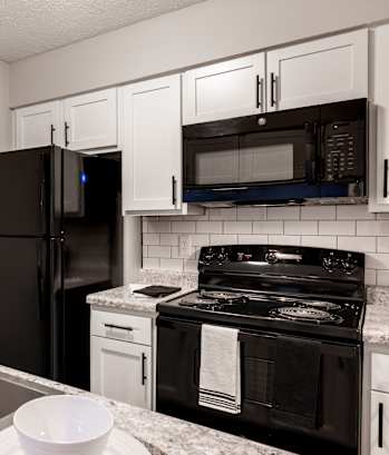a kitchen with black appliances and white cabinets and granite counter tops