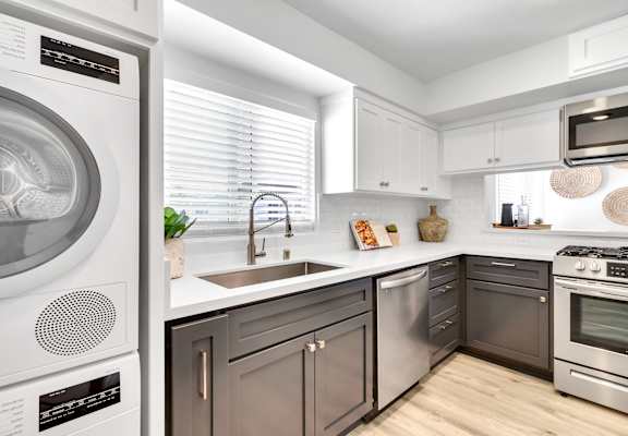 A modern kitchen with a washing machine on the left and a stove on the right.