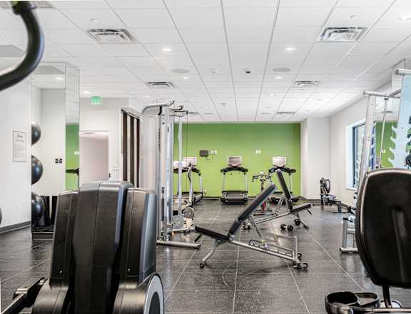 A gym with a variety of equipment including treadmills, weights, and exercise machines.