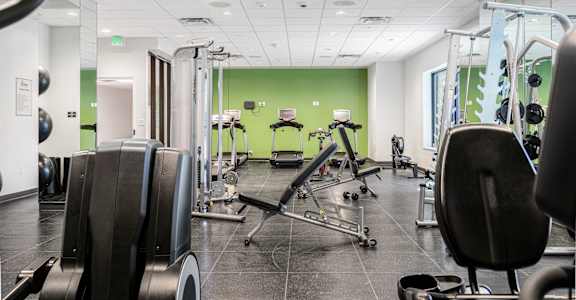 A gym with a variety of equipment including treadmills, weights, and exercise machines.