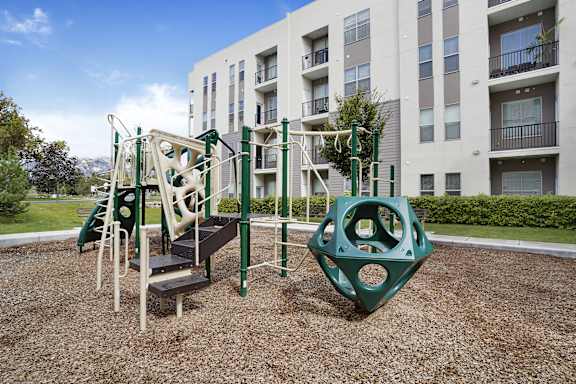 A playground with a green slide and a climbing frame.