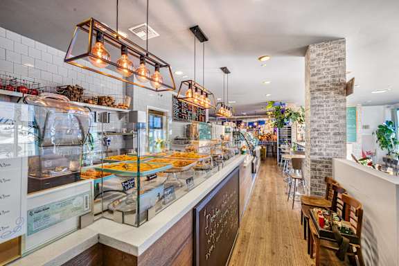 A modern cafe with a long counter and a variety of food displayed. at Esprit Apartments, California, 90292