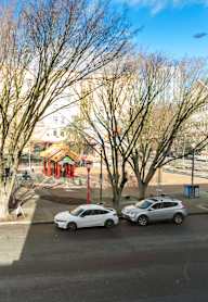 A parking lot with two cars and a tree in the foreground.