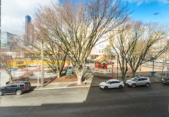 A parking lot with two cars and a tree in the foreground.
