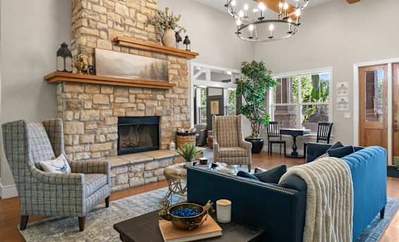 A living room with a stone fireplace and a blue couch. at Stonepost Lakeside Apartment Homes, Kansas, 66062