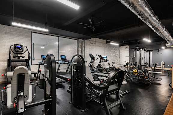 A gym with a variety of equipment including treadmills, stationary bikes, and weight machines.
