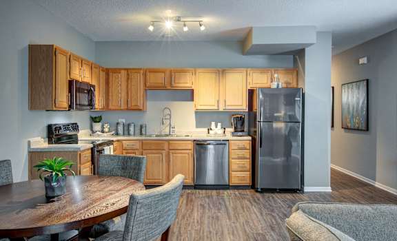 A kitchen with wooden cabinets and a grey refrigerator.