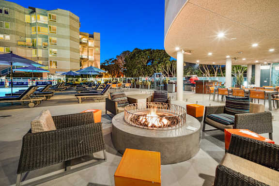 A fire pit sits in the middle of a patio with chairs around it. at Esprit Apartments, California