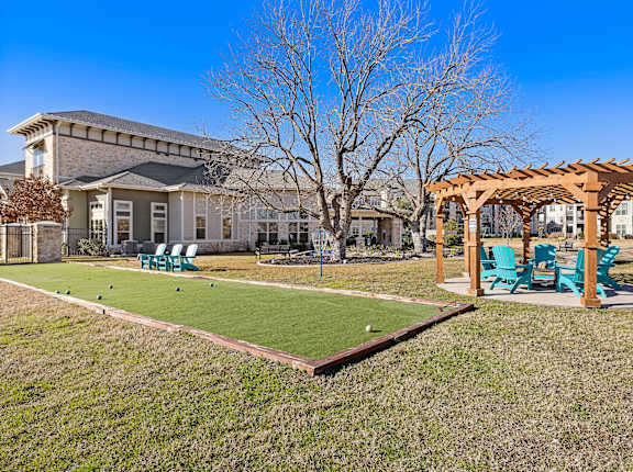 a backyard with a bocce ball court and a pergola at North Creek, Hutto, 78634