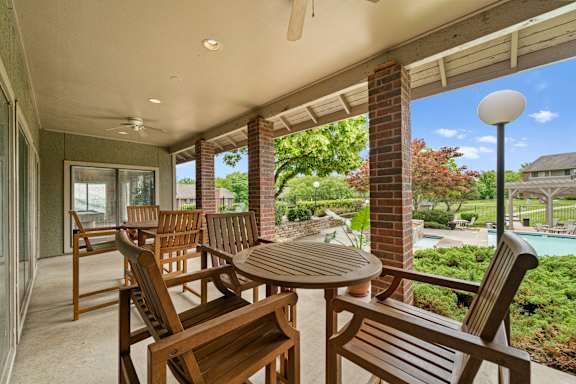 A patio with a table and chairs overlooking a pool.