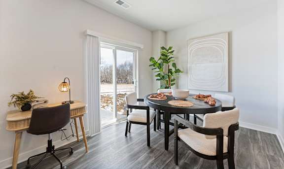 A dining room with a table set for two and a view of the outdoors.