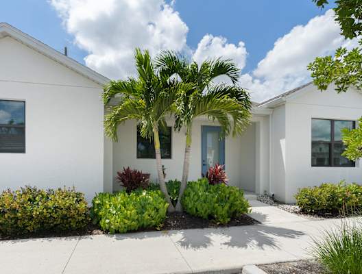 a white house with a palm tree in front of it at Odyssey, Fort Myers, FL, 33905
