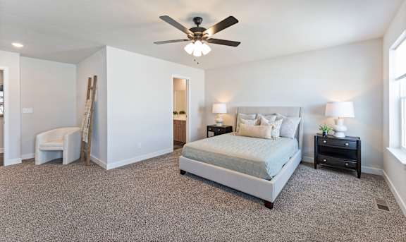 A bedroom with a bed, nightstands, and a ceiling fan.