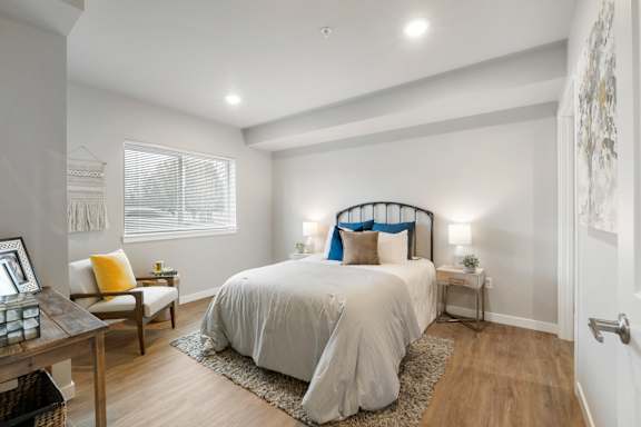 A bedroom with a large bed and a window with blinds.