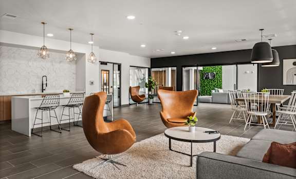 a living room with chairs and a table and a kitchen