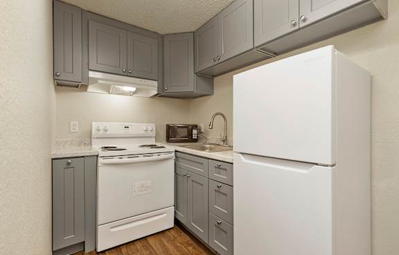 A white refrigerator is in a kitchen with grey cabinets.