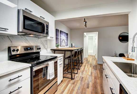 A modern kitchen with a black stove top oven and white cabinets at Woodlake Apartments, Kirkland, WA 98034