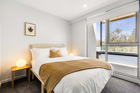A bedroom with a large bed and a window overlooking trees.