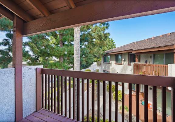 A wooden deck with a railing and a house in the background.