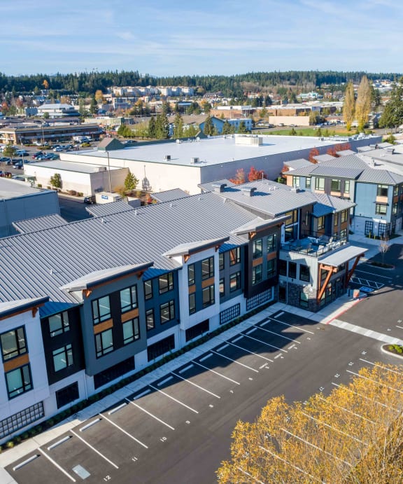 a rendering of a large apartment complex with a pond in the foreground and trees in the background at Rivulet, Silverdale Washington