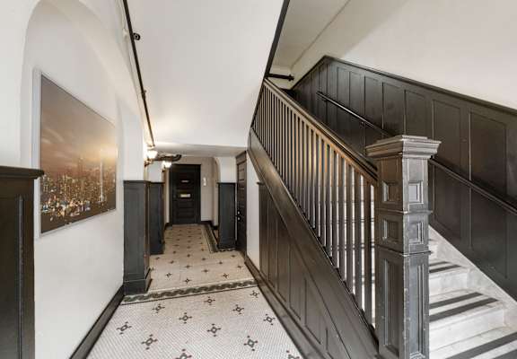 A hallway with a staircase and a painting on the wall.