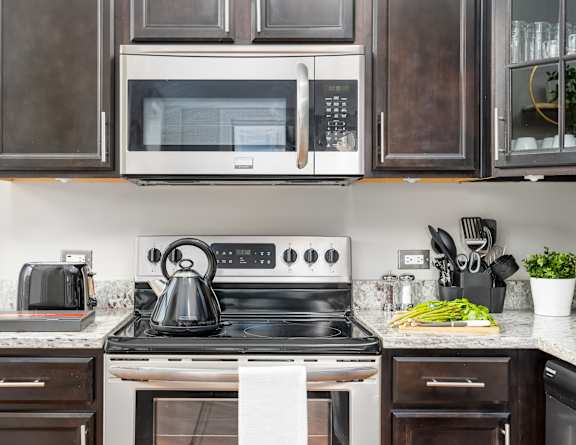 a kitchen with white appliances and black cabinets and a white stove and microwave