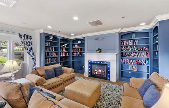 the living room has a fireplace and blue bookshelves