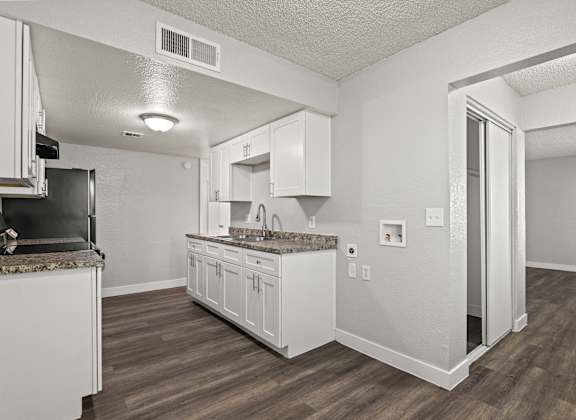 A kitchen with white cabinets and a granite countertop.