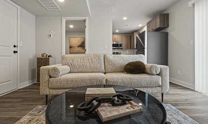 A modern living room with a beige couch and a glass coffee table.